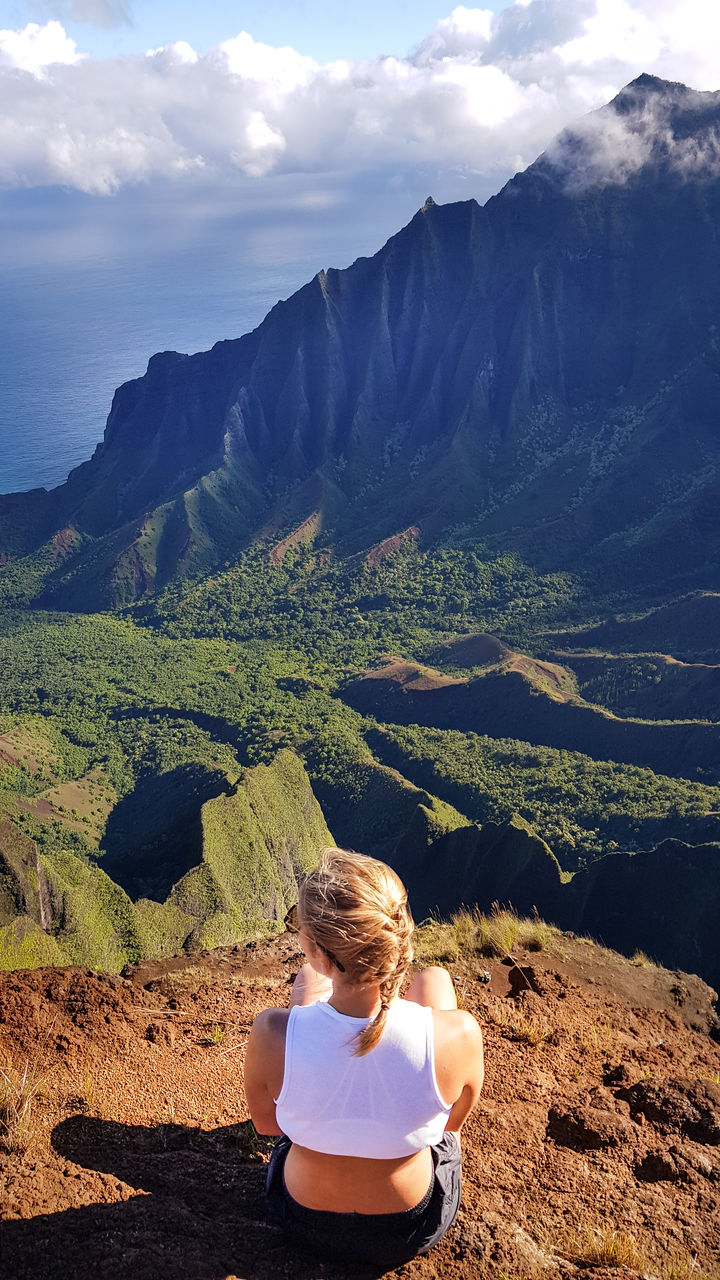 Rear view of woman looking at mountains against sky