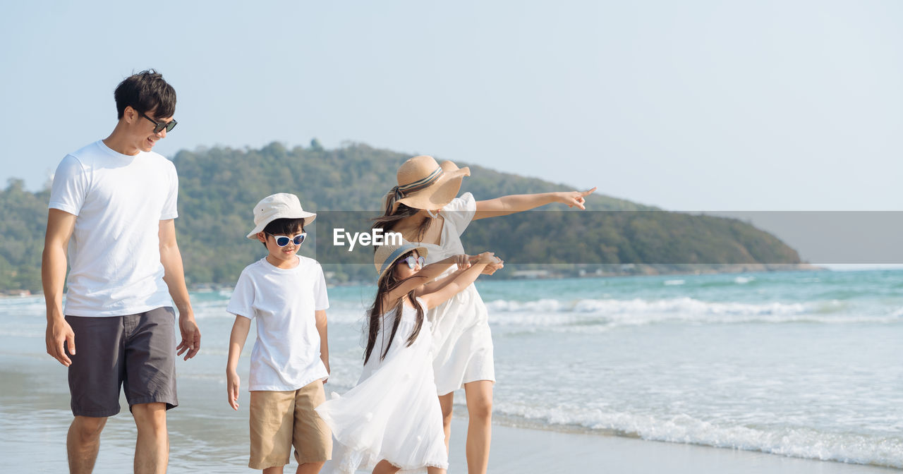 PEOPLE ON BEACH AGAINST CLEAR SKY