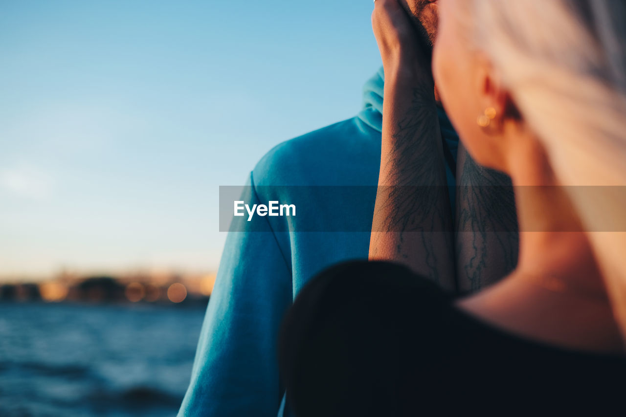 Woman embracing man against blue sky