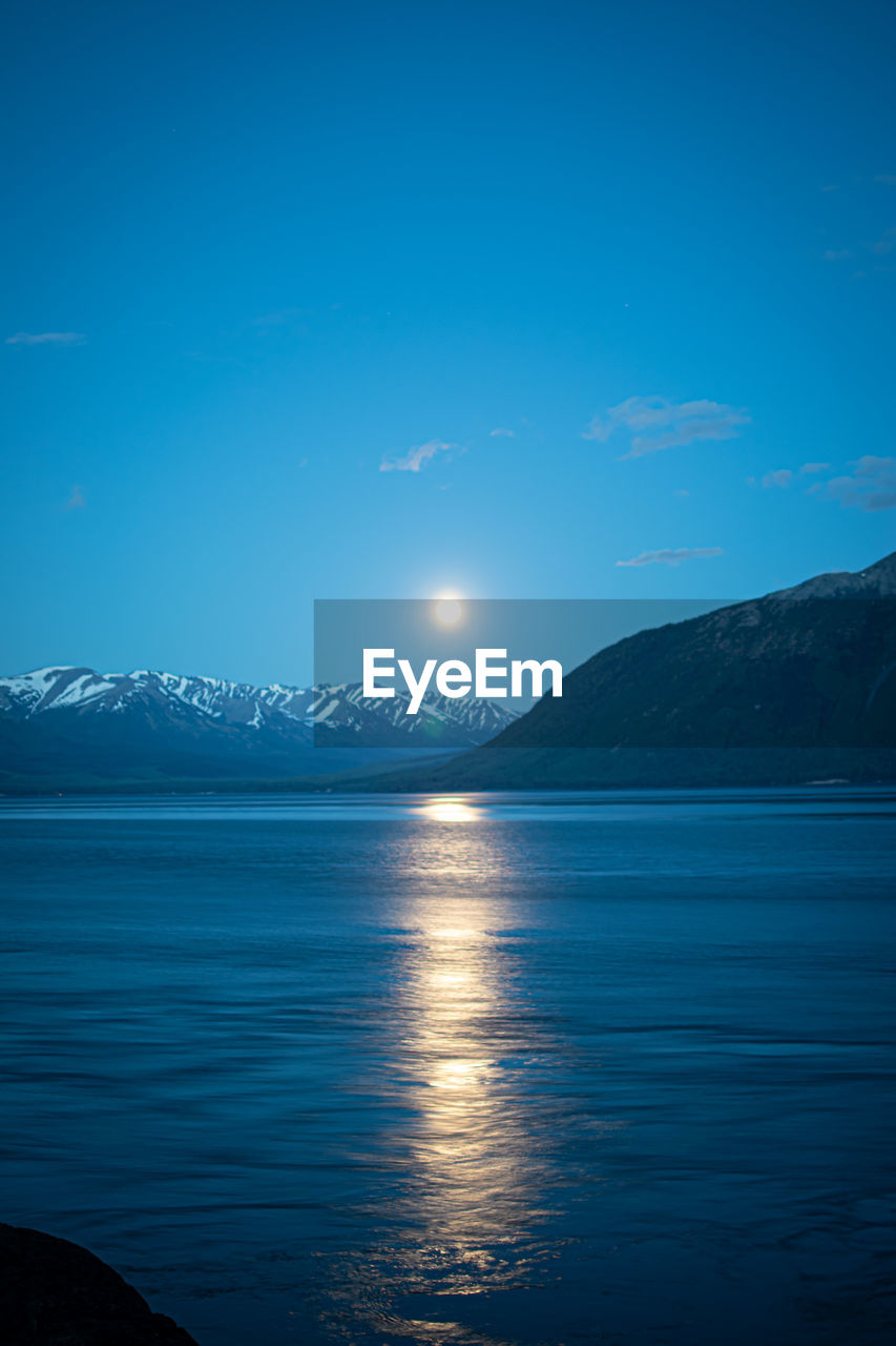 Full moon above the snow capped mountains of alaska