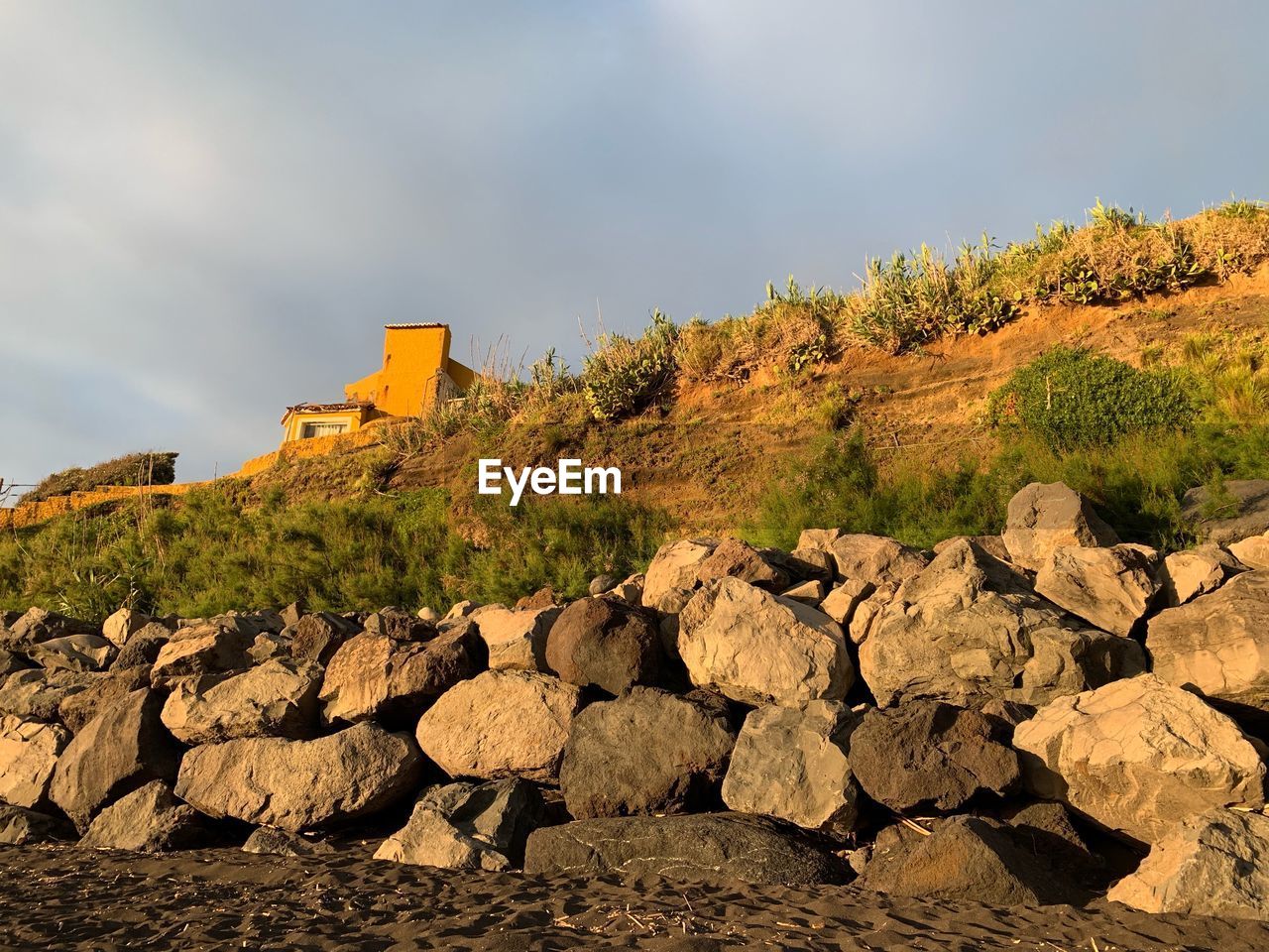 Stone wall by rocks against sky