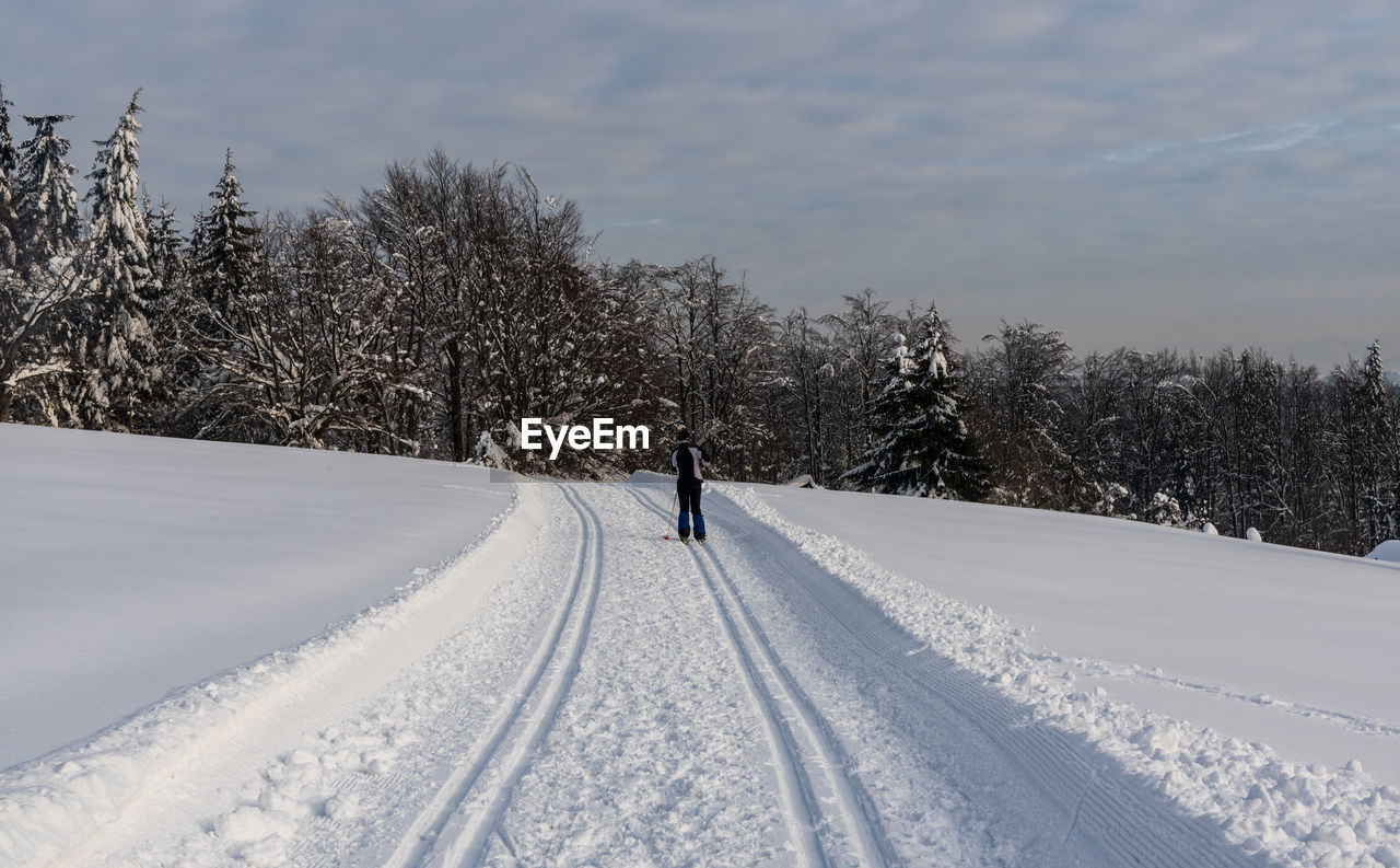 MAN WALKING ON SNOW COVERED FIELD