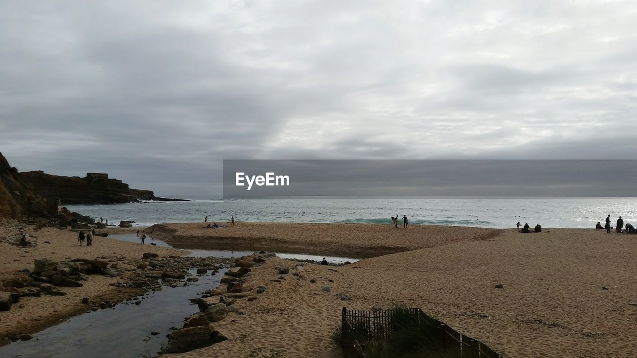 Scenic view of beach against cloudy sky