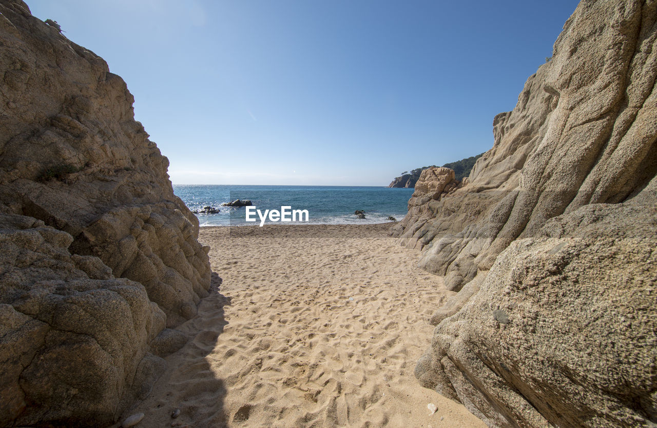 ROCK FORMATION ON BEACH AGAINST CLEAR SKY