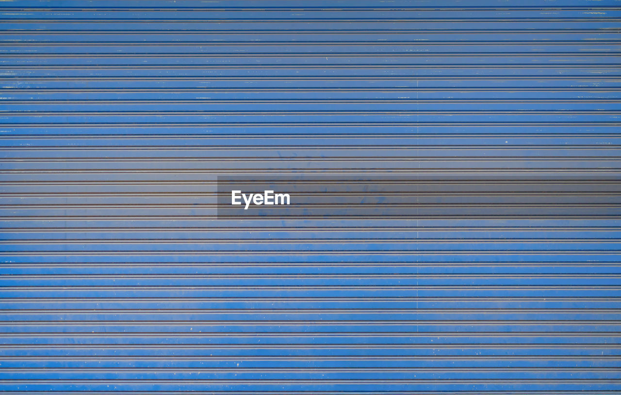 FULL FRAME SHOT OF BLUE SHUTTER WITH METAL GRATE