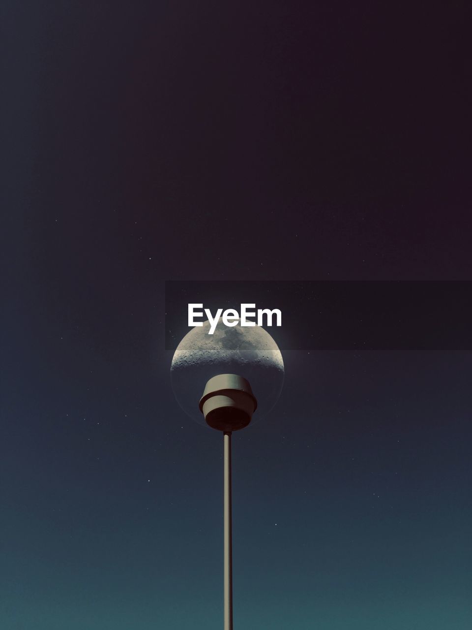 Low angle view of street light against moon in sky at night