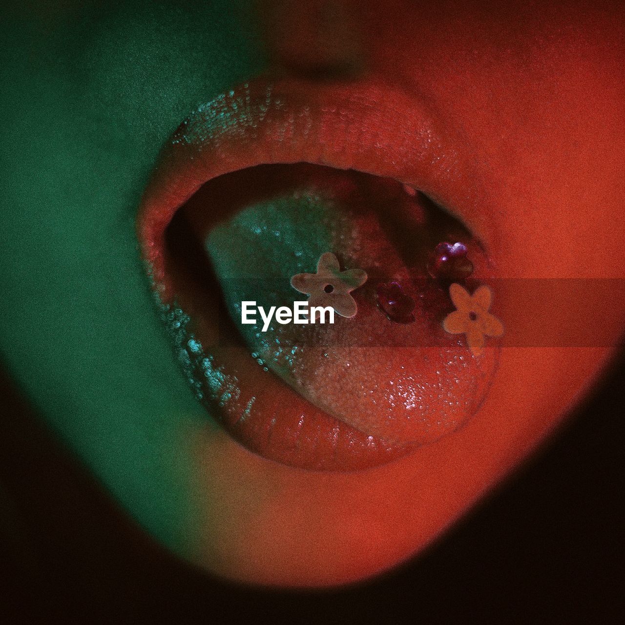 Close-up of woman with artificial flowers on tongue