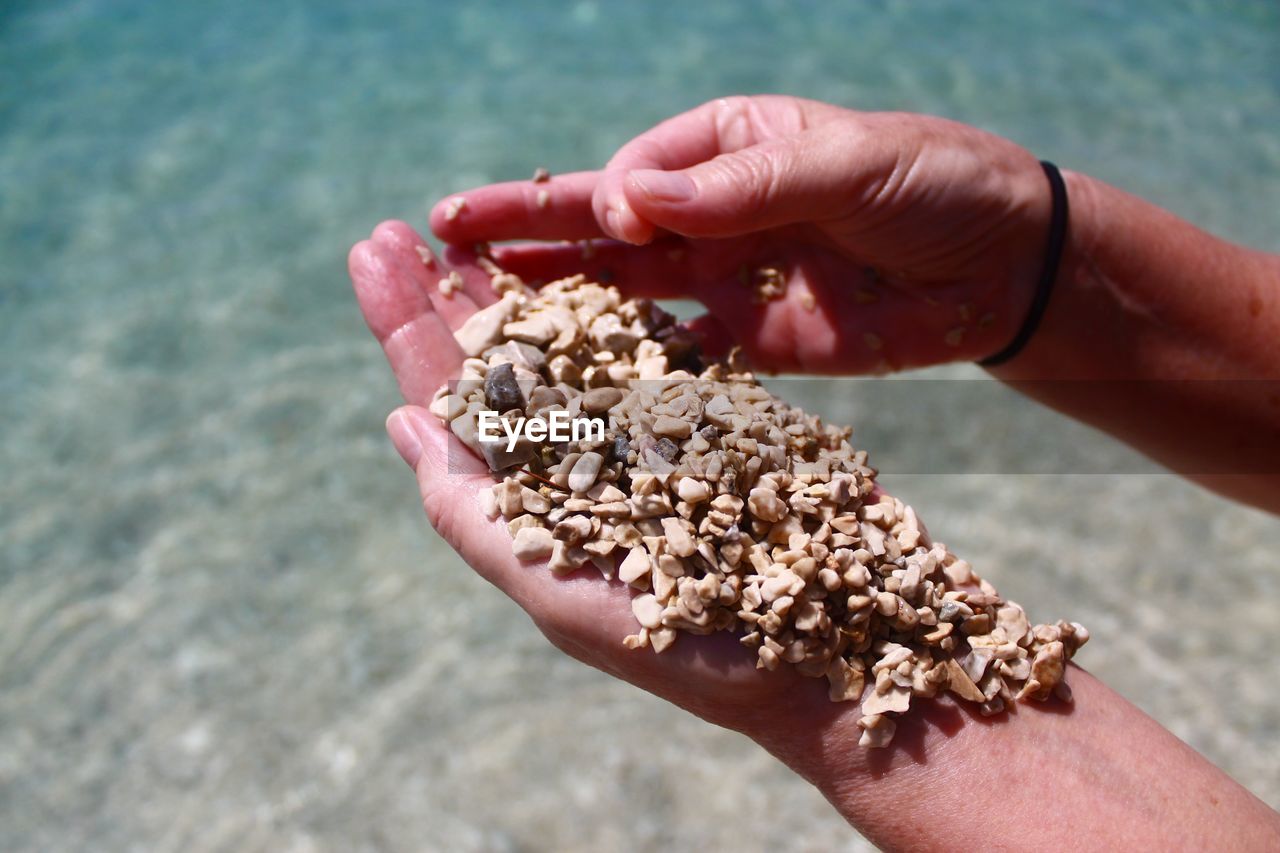 Cropped hand holding stones at beach