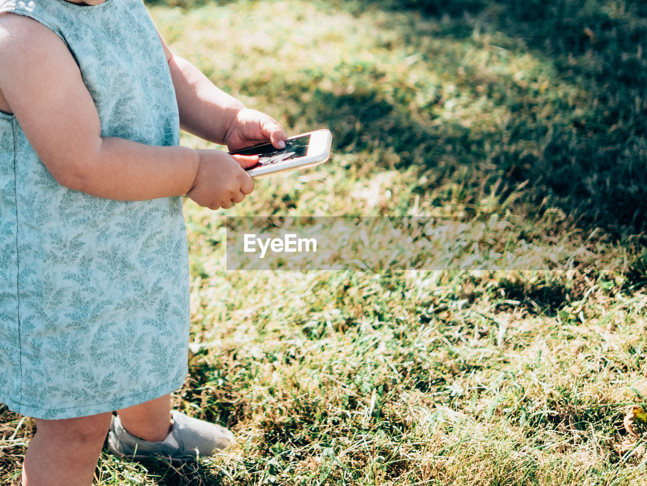 Child using mobile phone in grass field