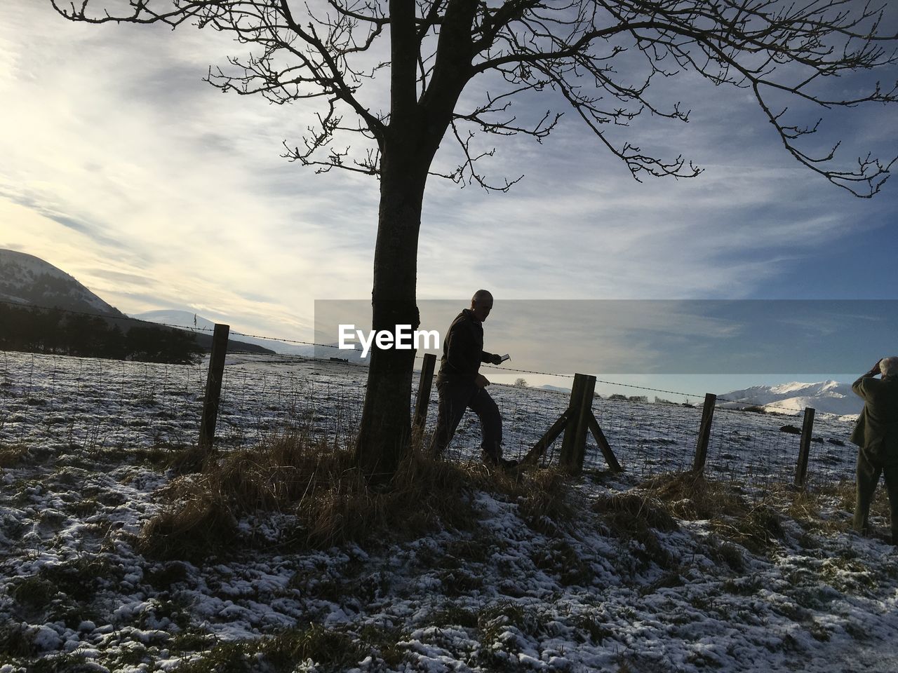 Man standing by tree against sky during winter