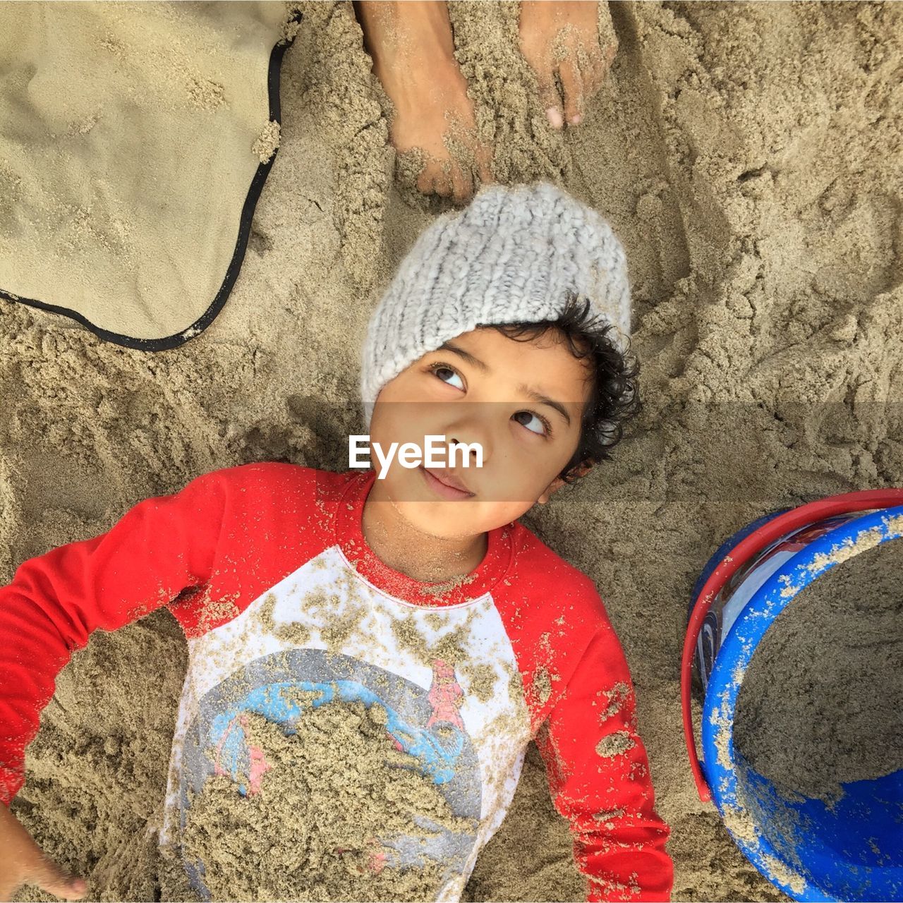 High angle view of cute boy lying on sand at beach