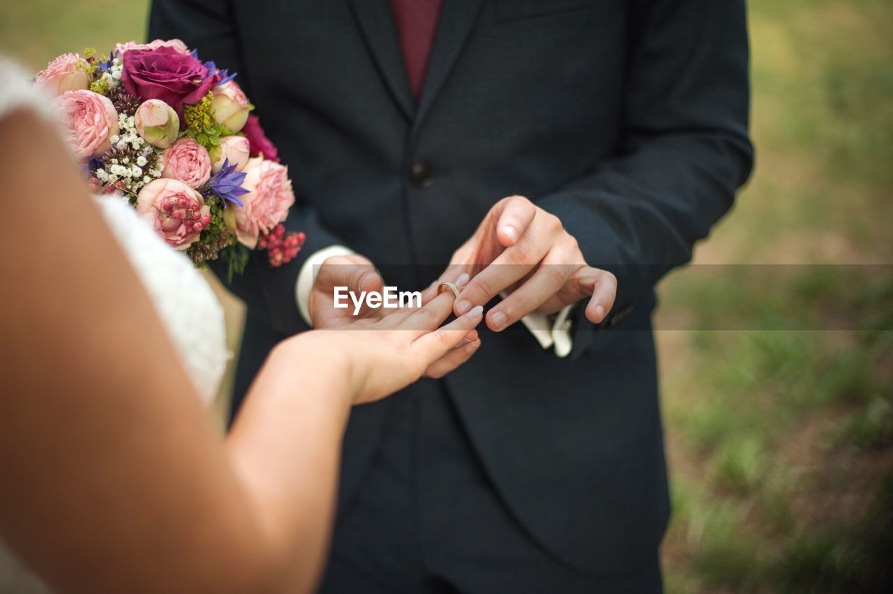 Groom putting wedding ring in finger of bride