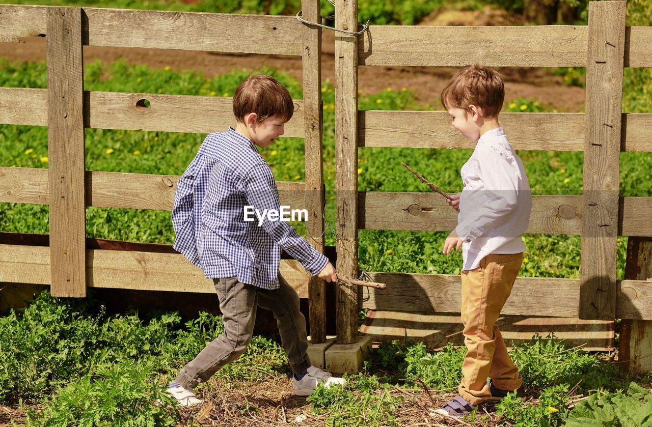 Boy standing by fence in farm