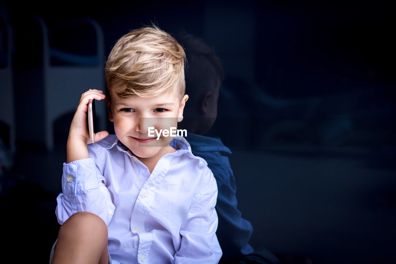 Smiling boy using cell phone and communicating against the wall. copy space.