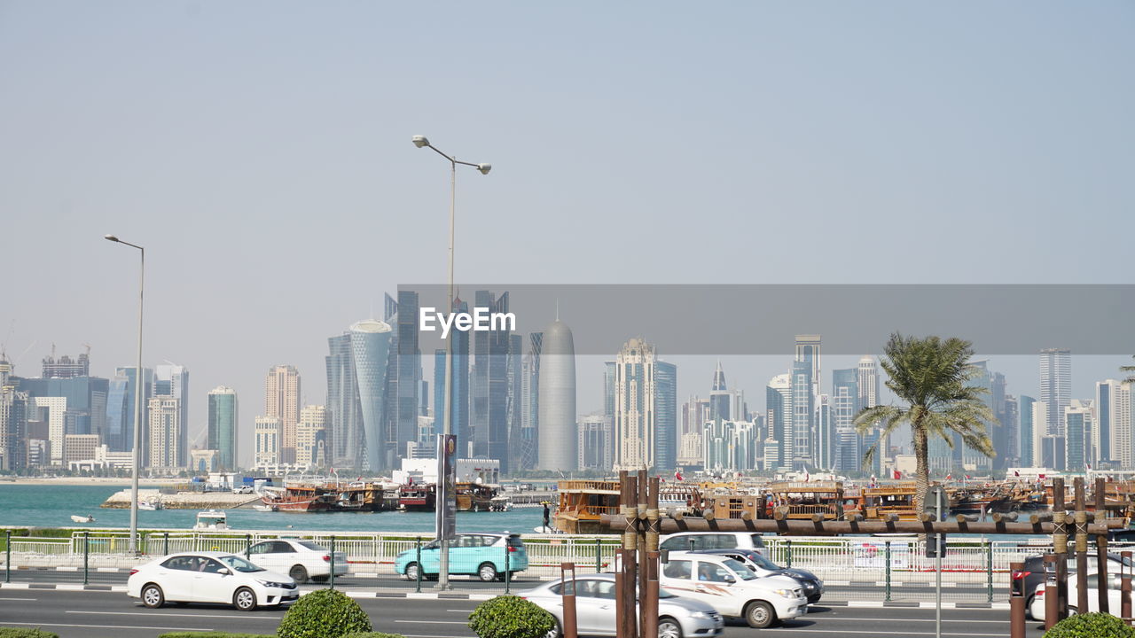 CARS ON ROAD BY BUILDINGS AGAINST CLEAR SKY IN CITY