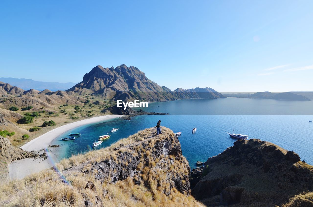 Scenic view of sea and mountains against blue sky