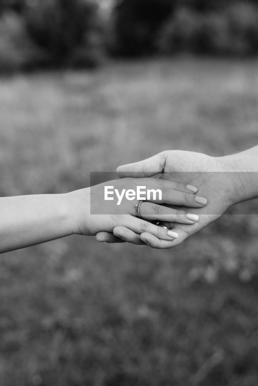 Cropped image of husband and wife stacking hands outdoors