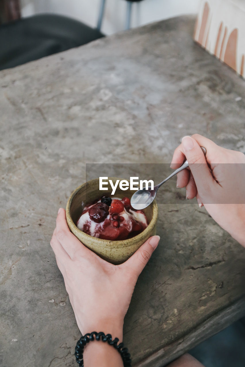 Cropped hand eating sweet food on table