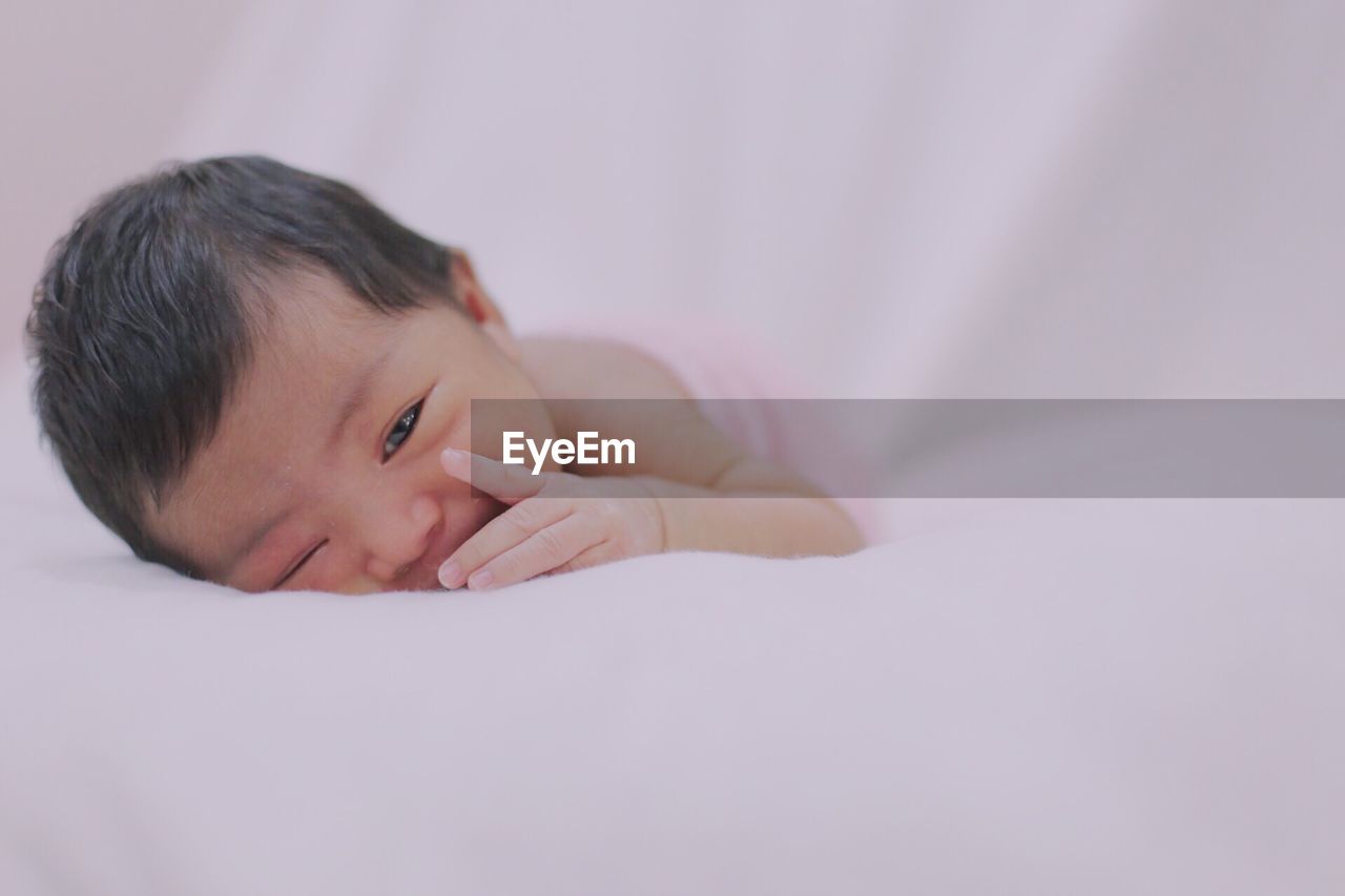 PORTRAIT OF BABY BOY LYING ON BED