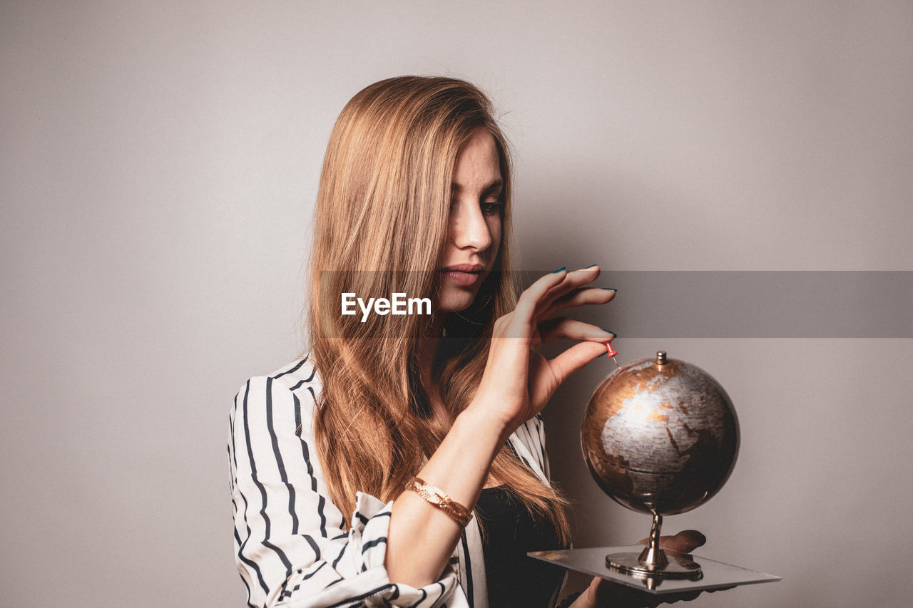 Woman looking at globe against gray background