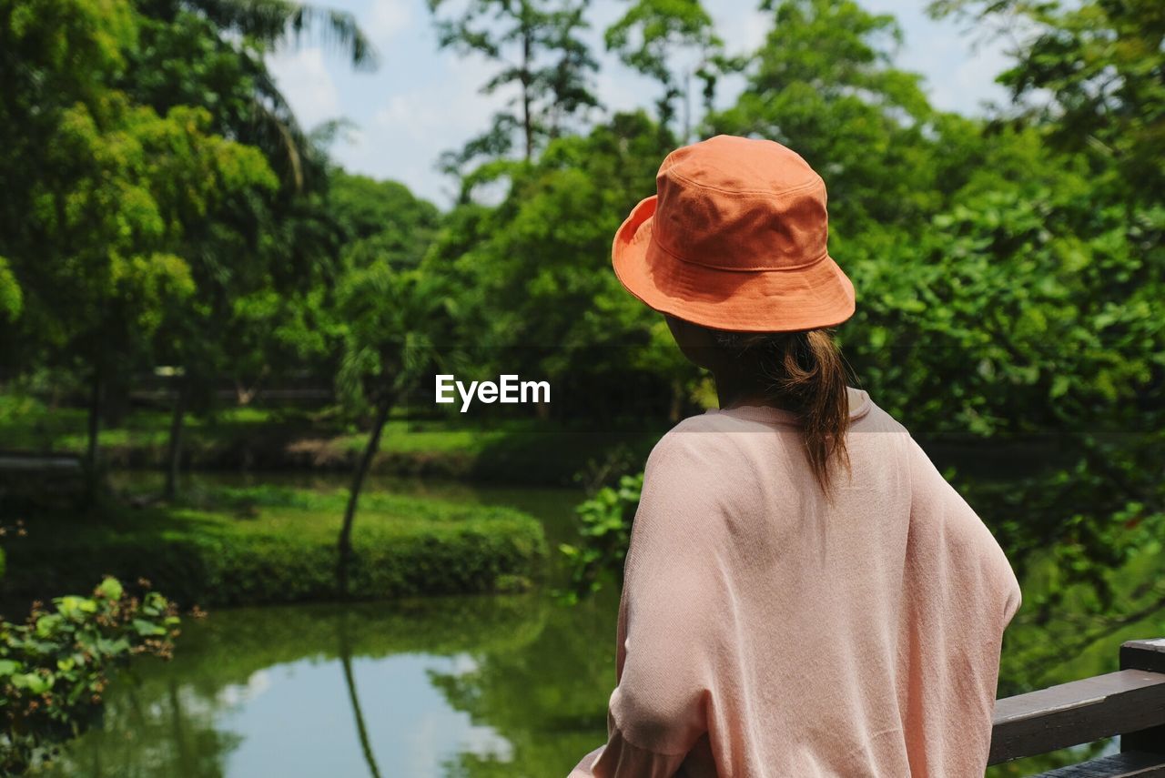 Rear view of woman looking at lake against trees