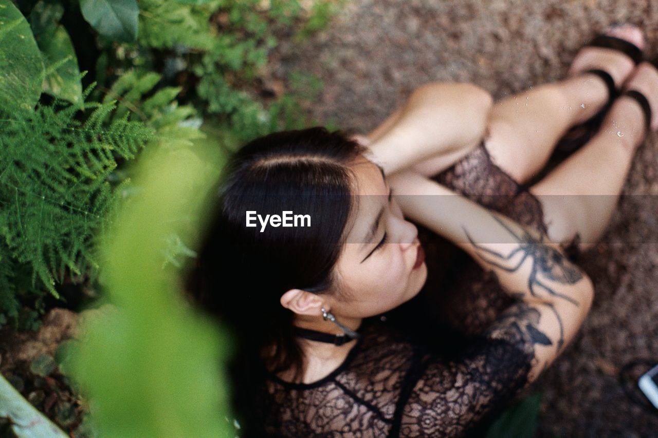 High angle view of thoughtful young woman sitting on field