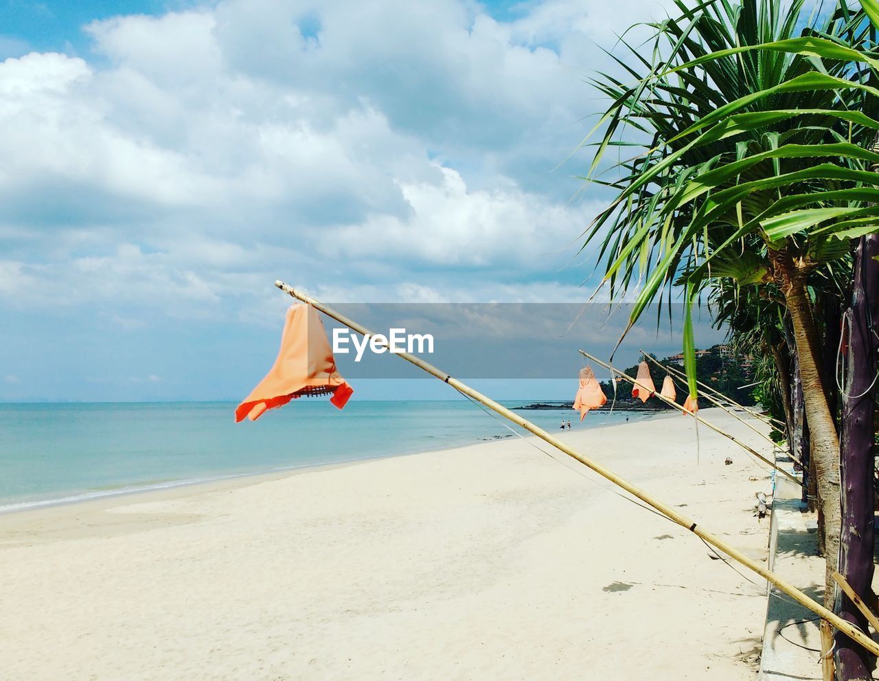 View of calm beach against cloudy sky