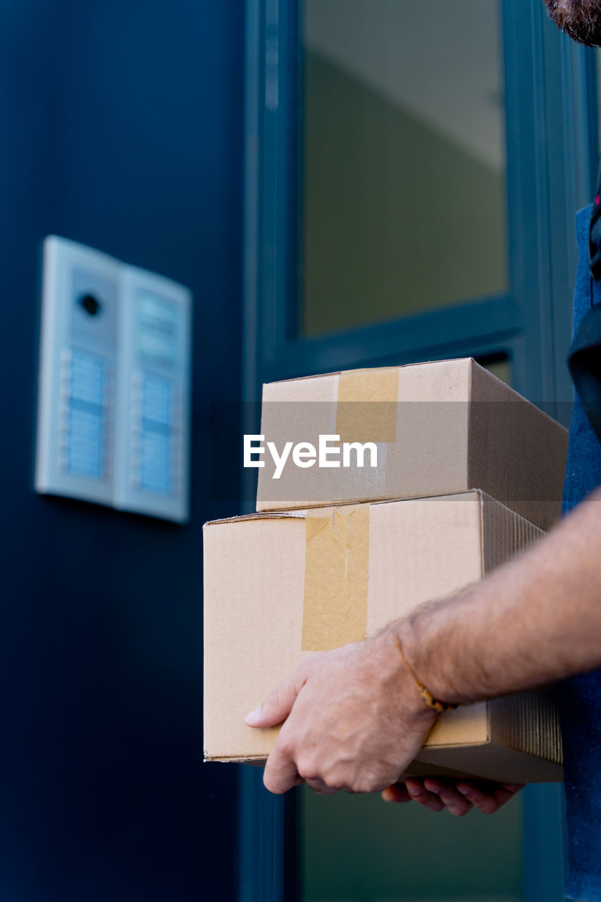 Midsection of man holding parcel against wall