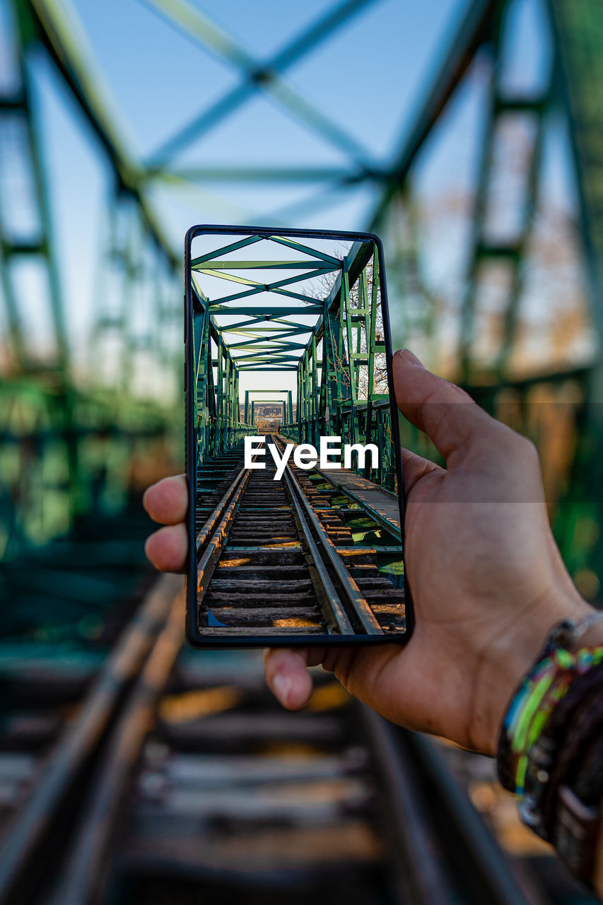 CLOSE-UP OF PERSON HOLDING RAILROAD TRACKS