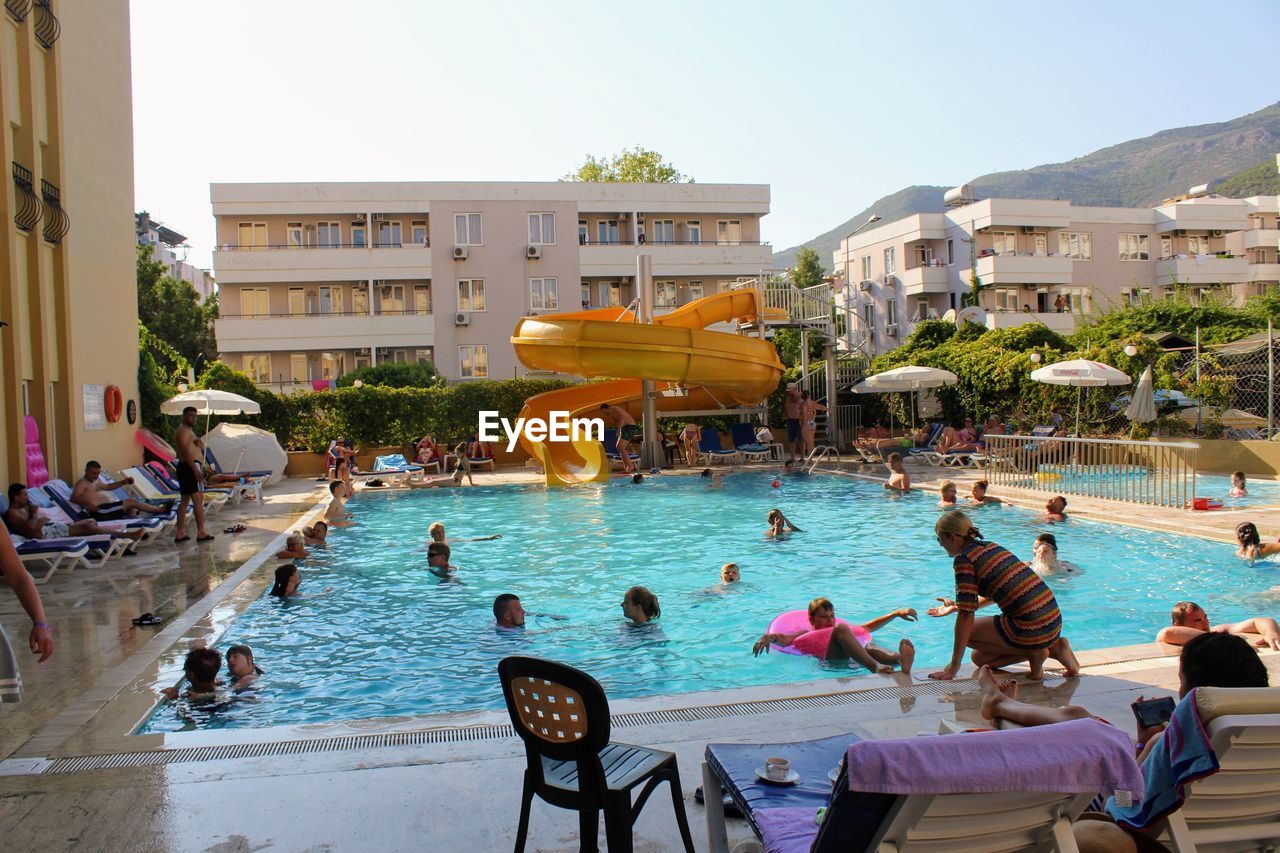 PEOPLE AT SWIMMING POOL AGAINST SKY