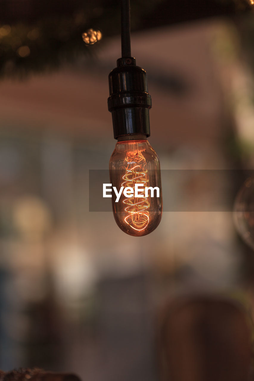 Close-up of lit light bulb against blurred background