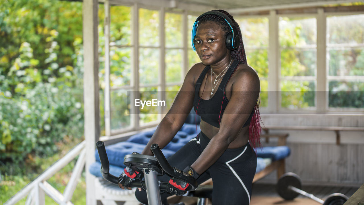 African woman exercising at home outdoors on an exercise bike during autumn