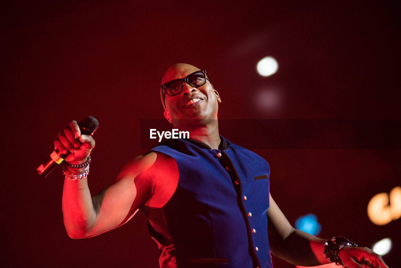 LOW ANGLE VIEW OF YOUNG MAN HOLDING EYEGLASSES