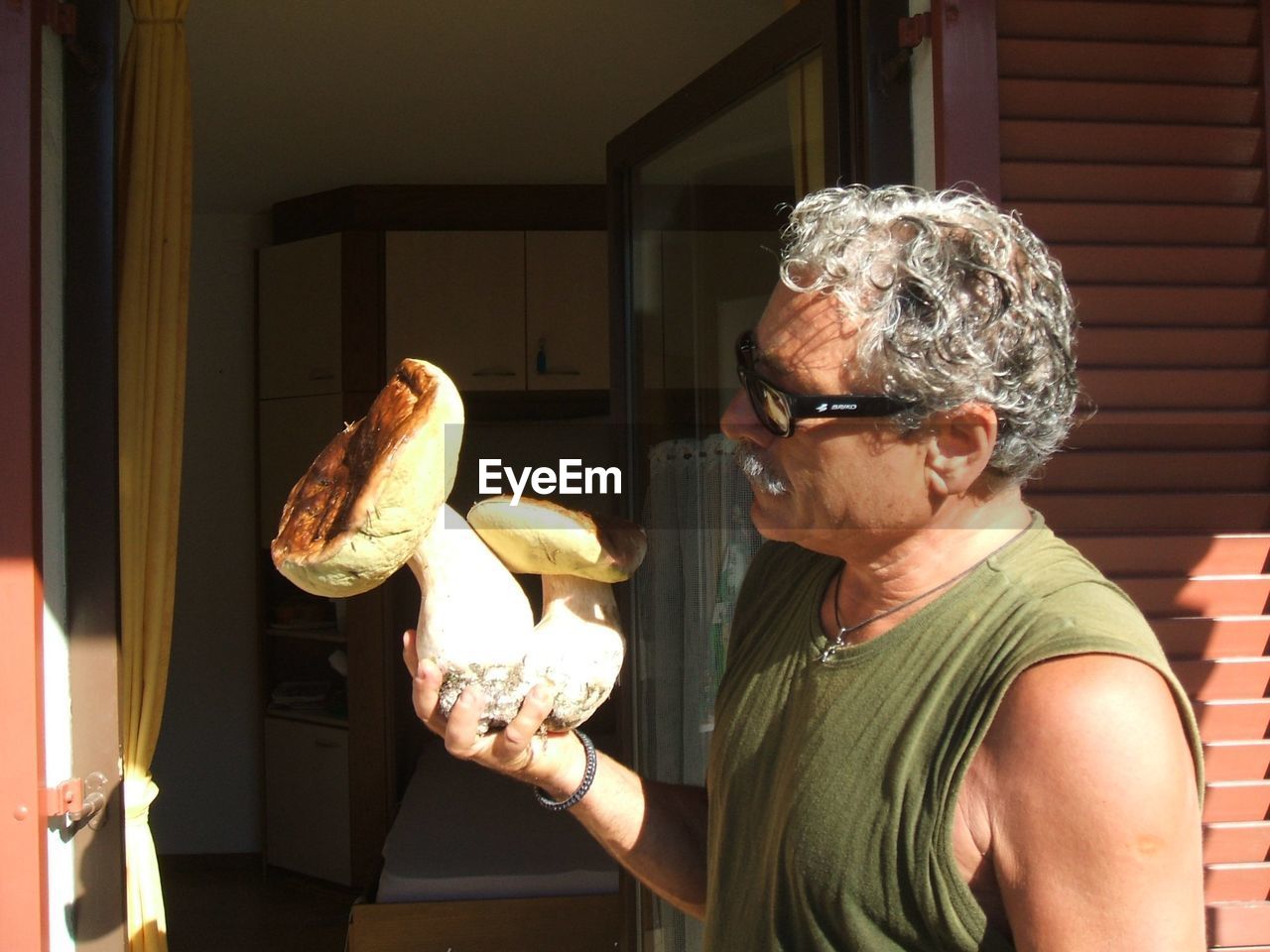 Close-up of man holding mushroom at home