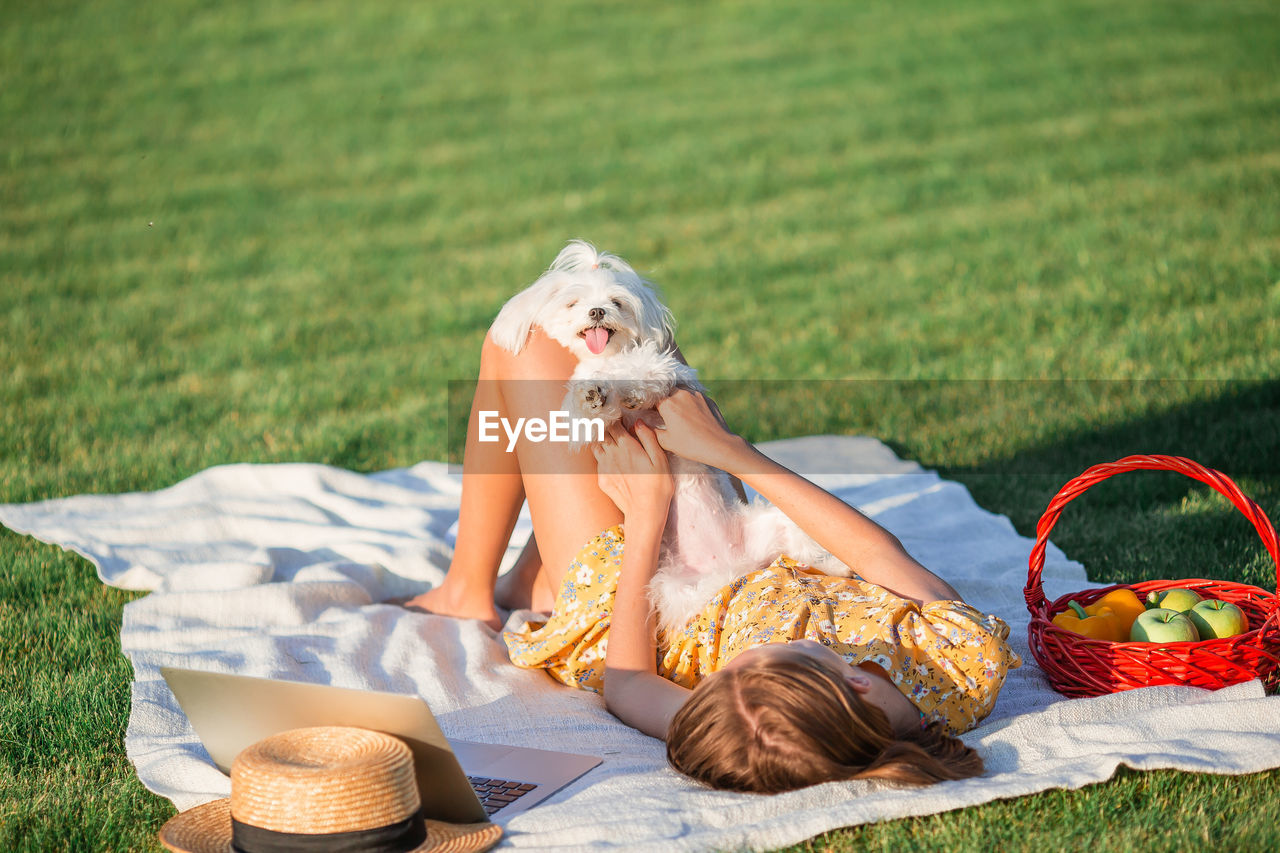 Girl lying on grass with dog at park
