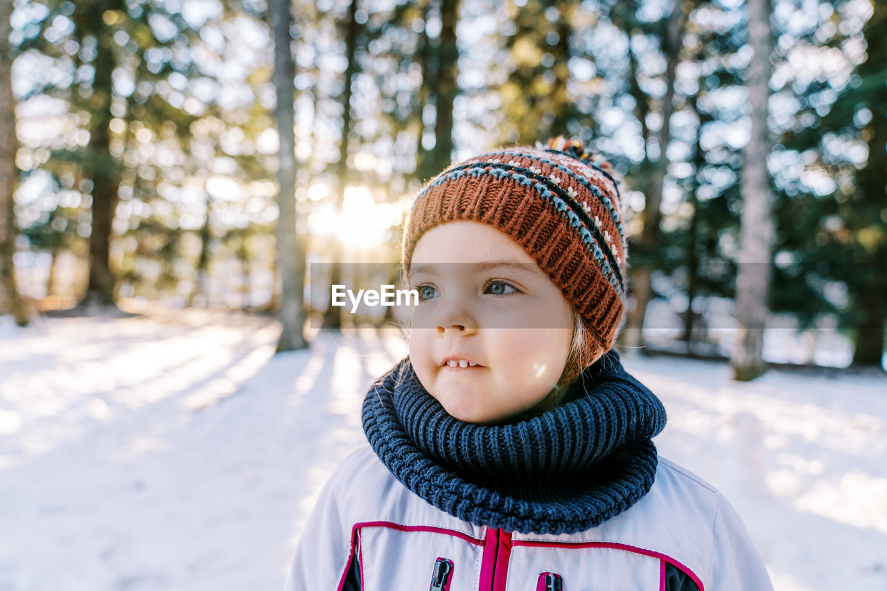 portrait of smiling boy standing in snow