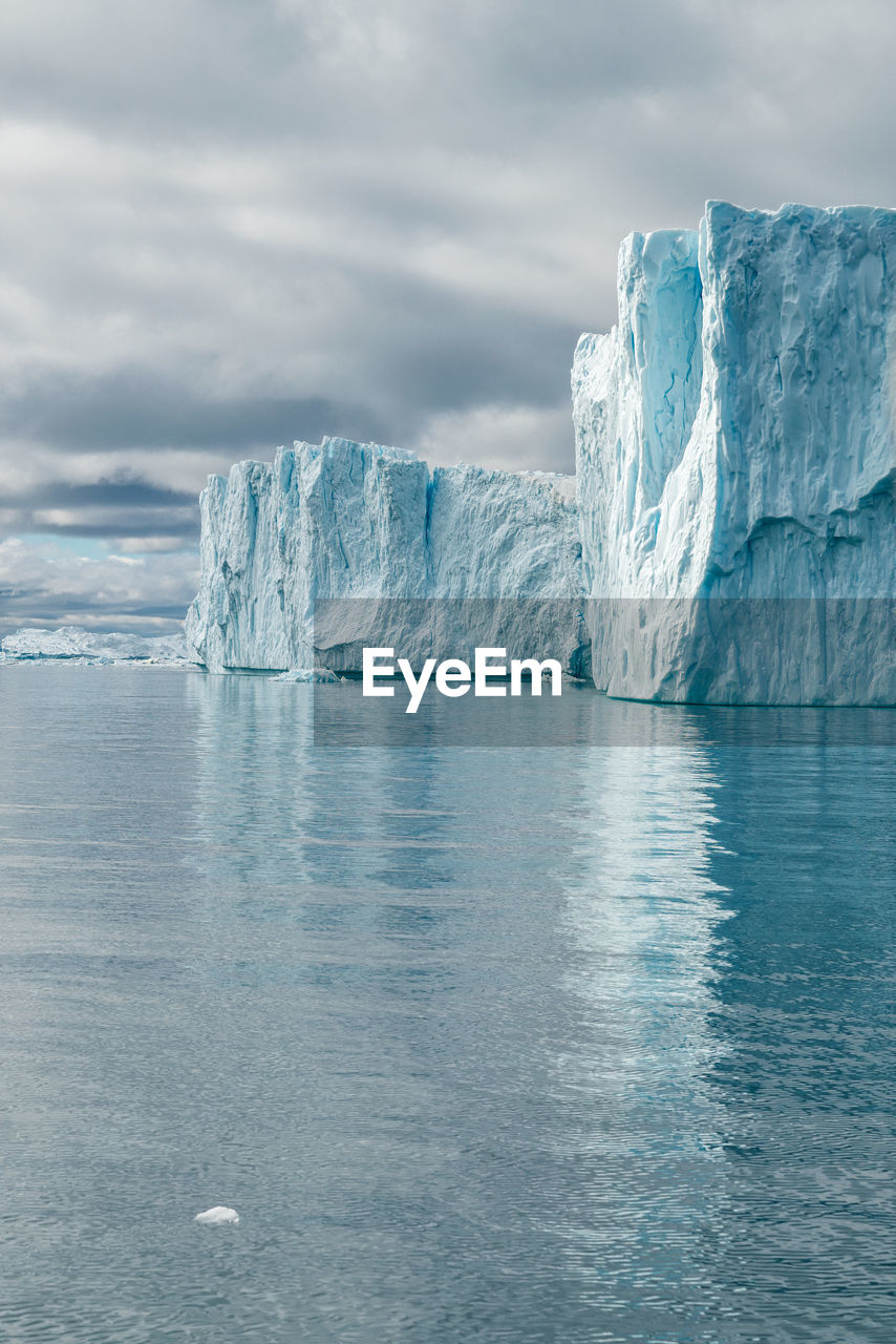 Icebergs against cloudy sky