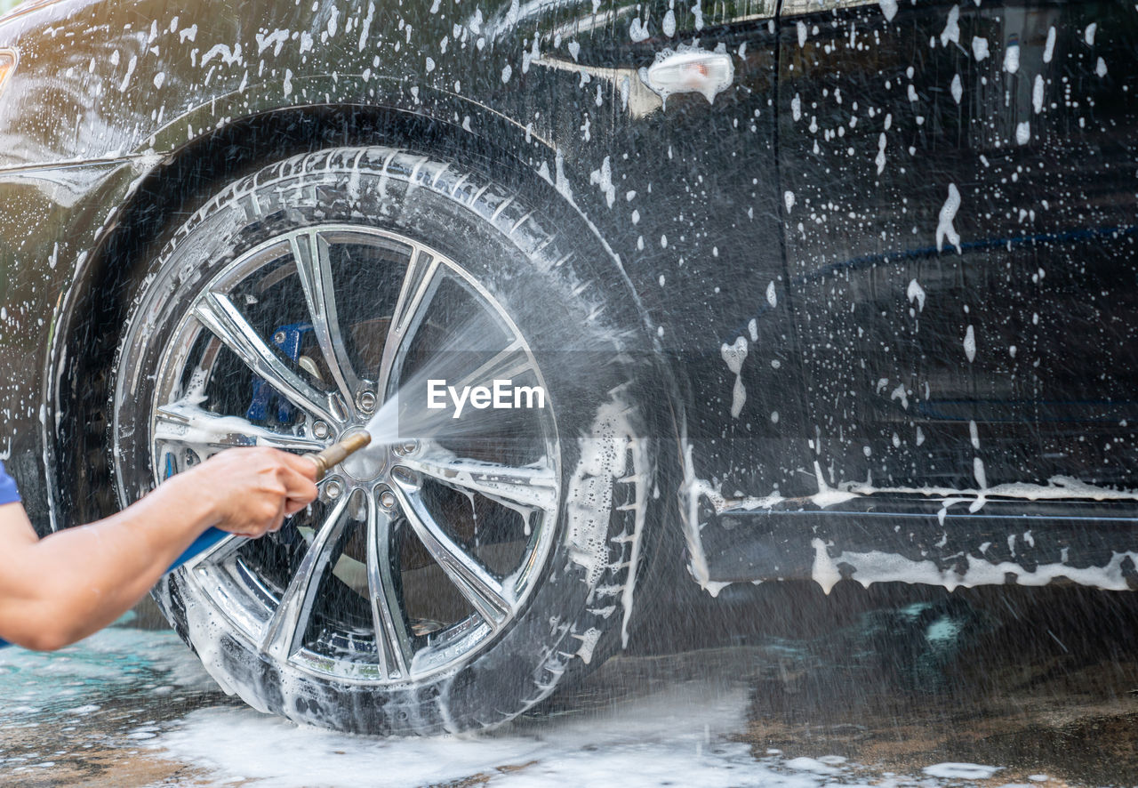 Manual car wash with pressurized water home outdoor. spray cleanning wheel.