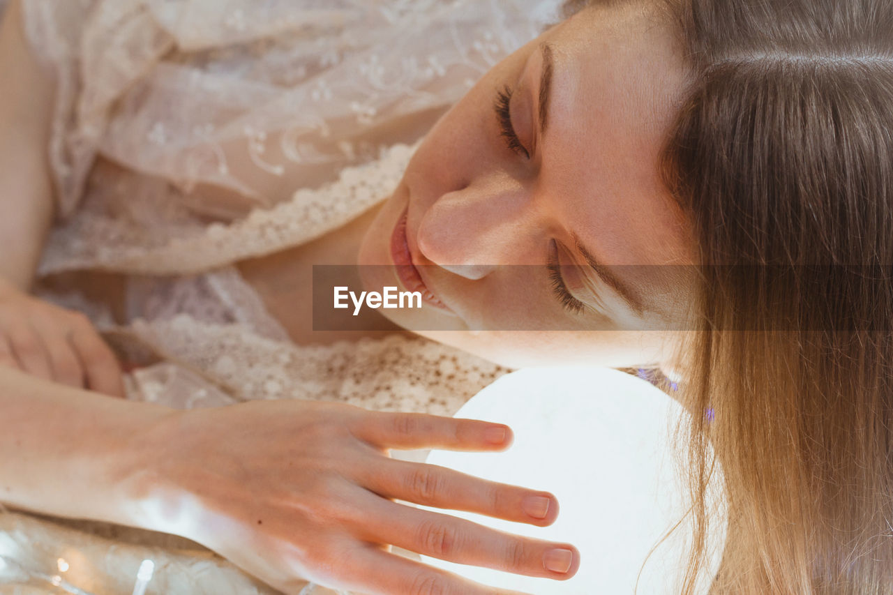 Close up sleeping woman with head on glowing ball light portrait picture