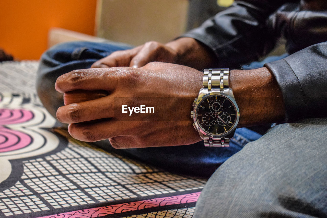 Close-up of man wearing wristwatch on bed at home