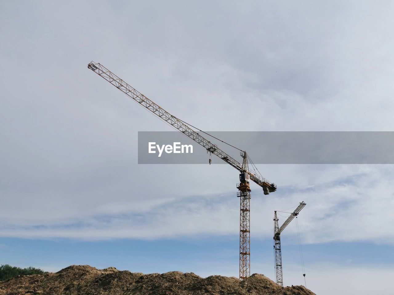 Low angle view of crane at construction site against sky