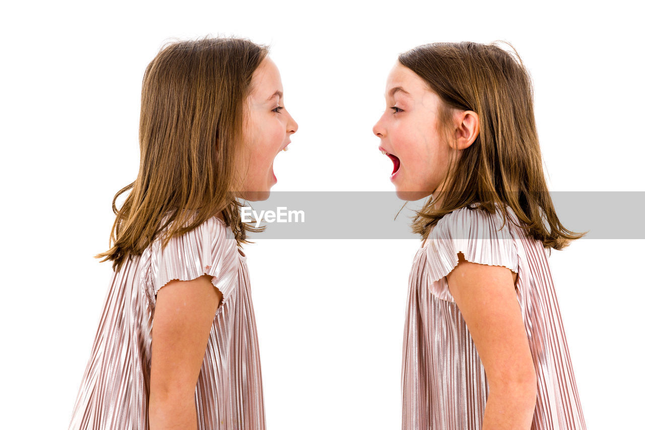 Side view of twin girls against white background