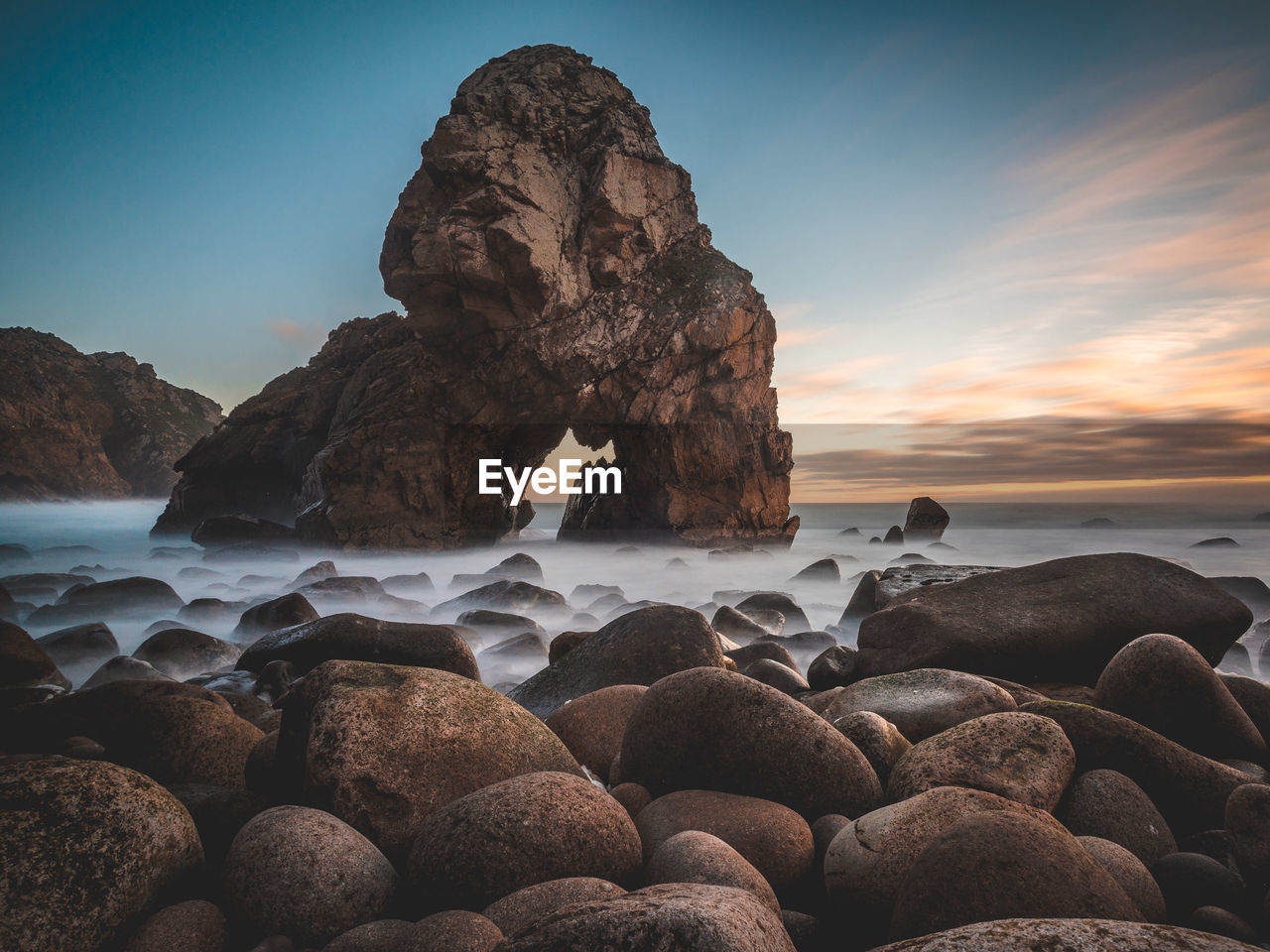 ROCKS ON BEACH AGAINST SKY AT SUNSET