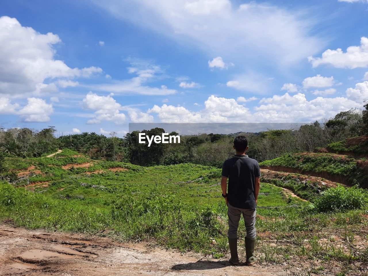 REAR VIEW OF MAN STANDING AGAINST SKY