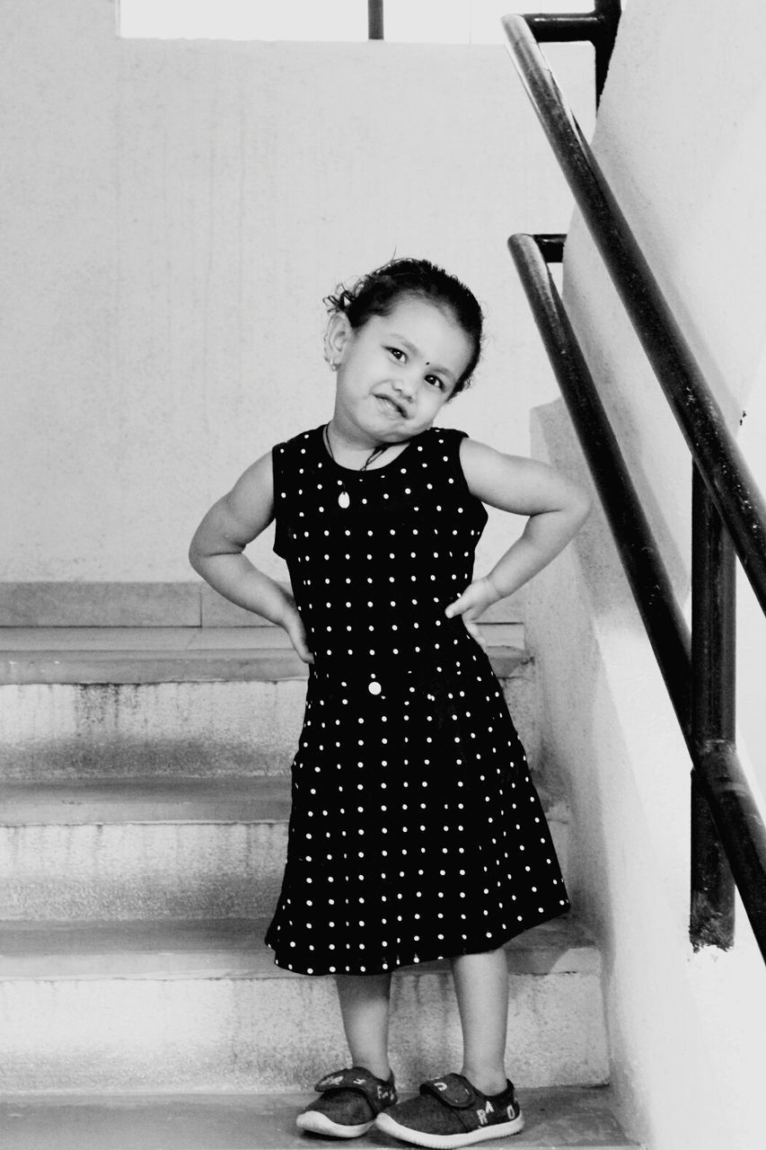 Portrait of girl with hands on hips standing on steps