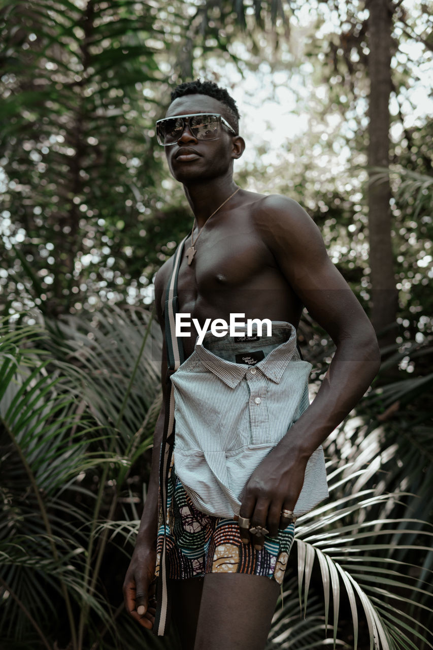 YOUNG MAN STANDING IN FOREST