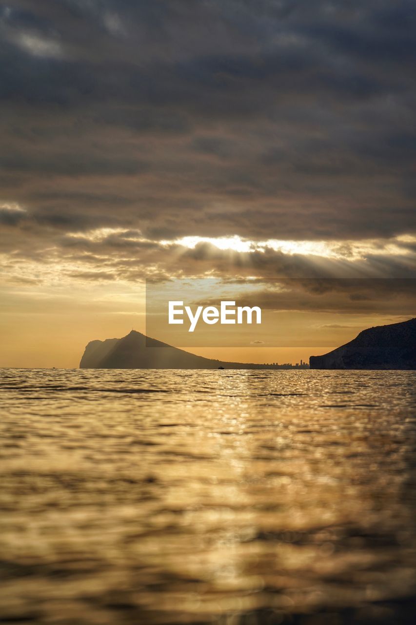 Scenic view of sea against dramatic sky during sunset