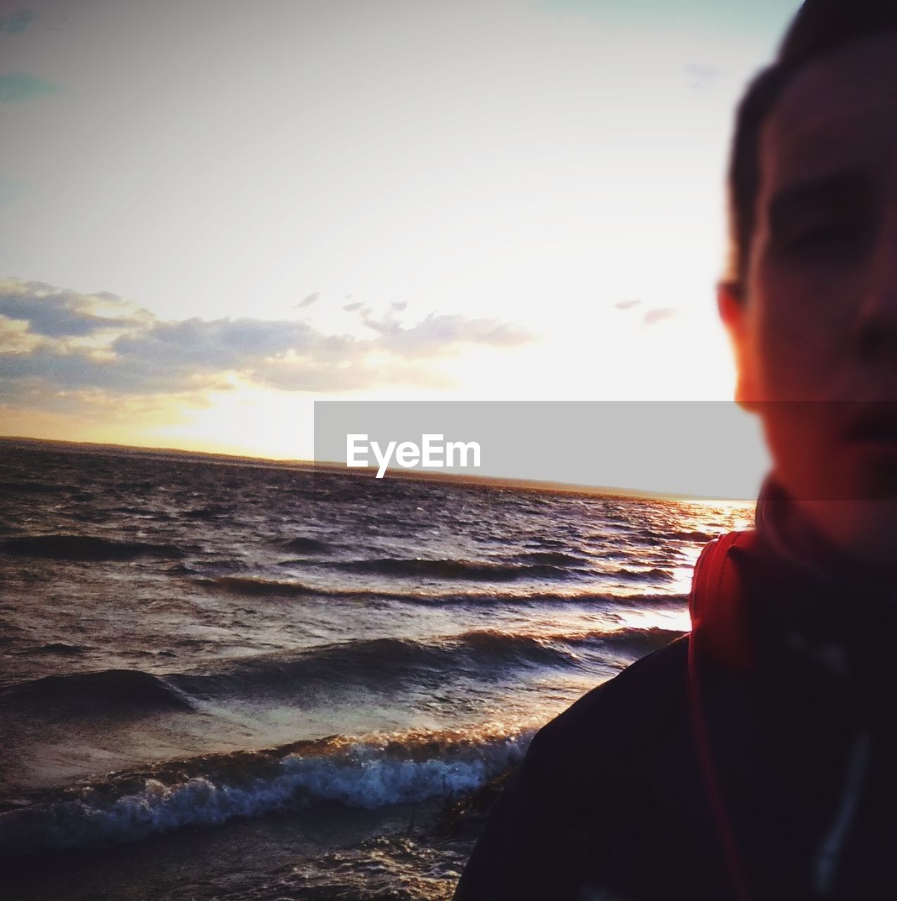 MAN LOOKING AT SEA DURING SUNSET