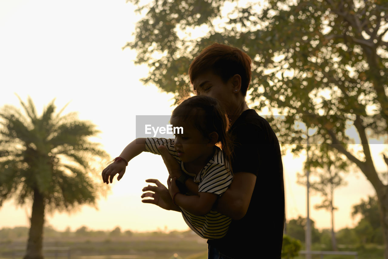 side view of mother and daughter standing against sky