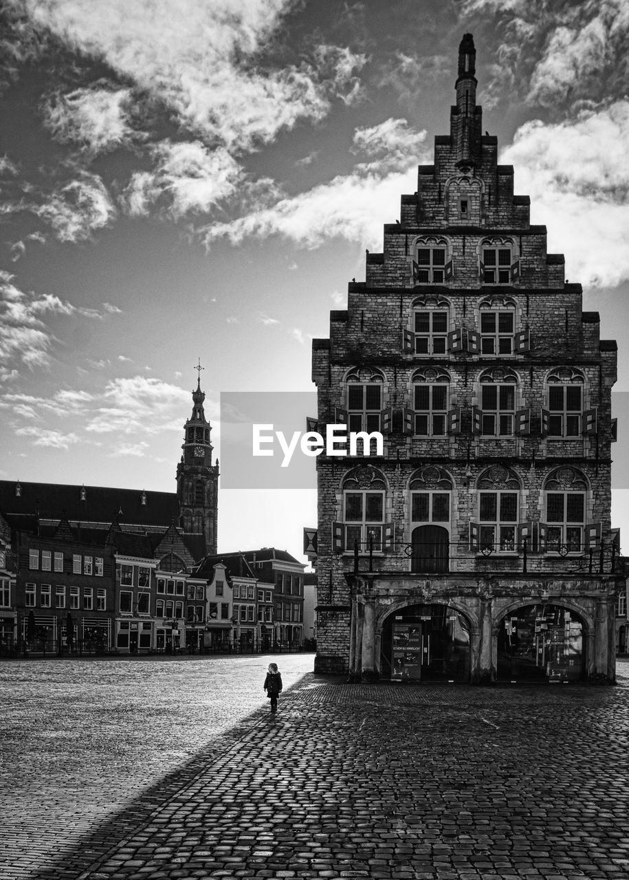 Full length of girl walking by historical building against sky